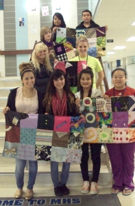 Some of the students from Fashion Design & Merchandising display their quilts before they're delivered to Iowa River Hospice.
